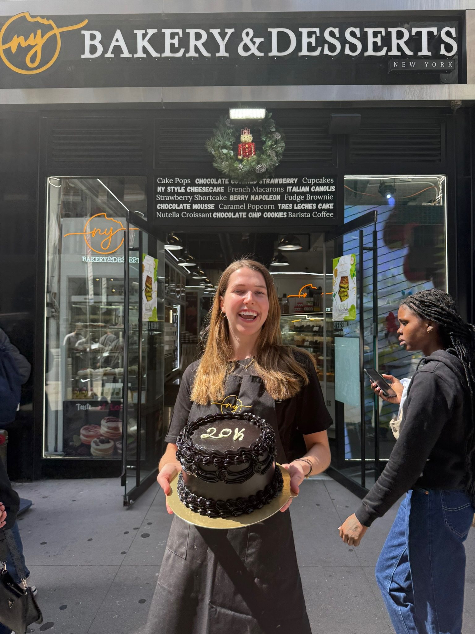 Erika holding a cake outside NY Bakery and Desserts