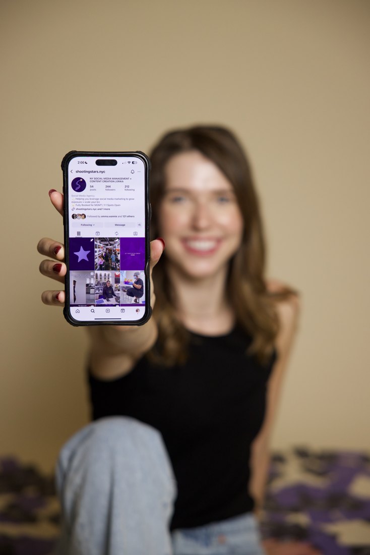 Erika holding up a phone showing the Shooting Stars Instagram
